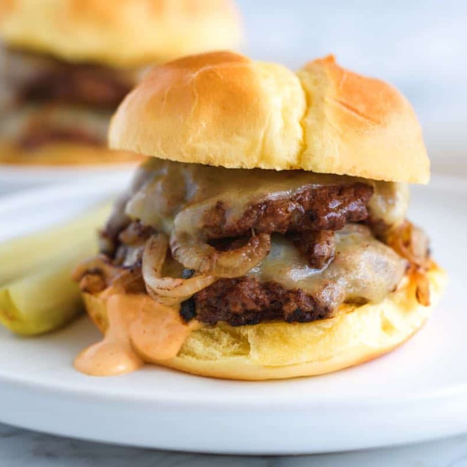 A double smash burger with melted cheese, caramelized onions, and special sauce on a brioche bun.