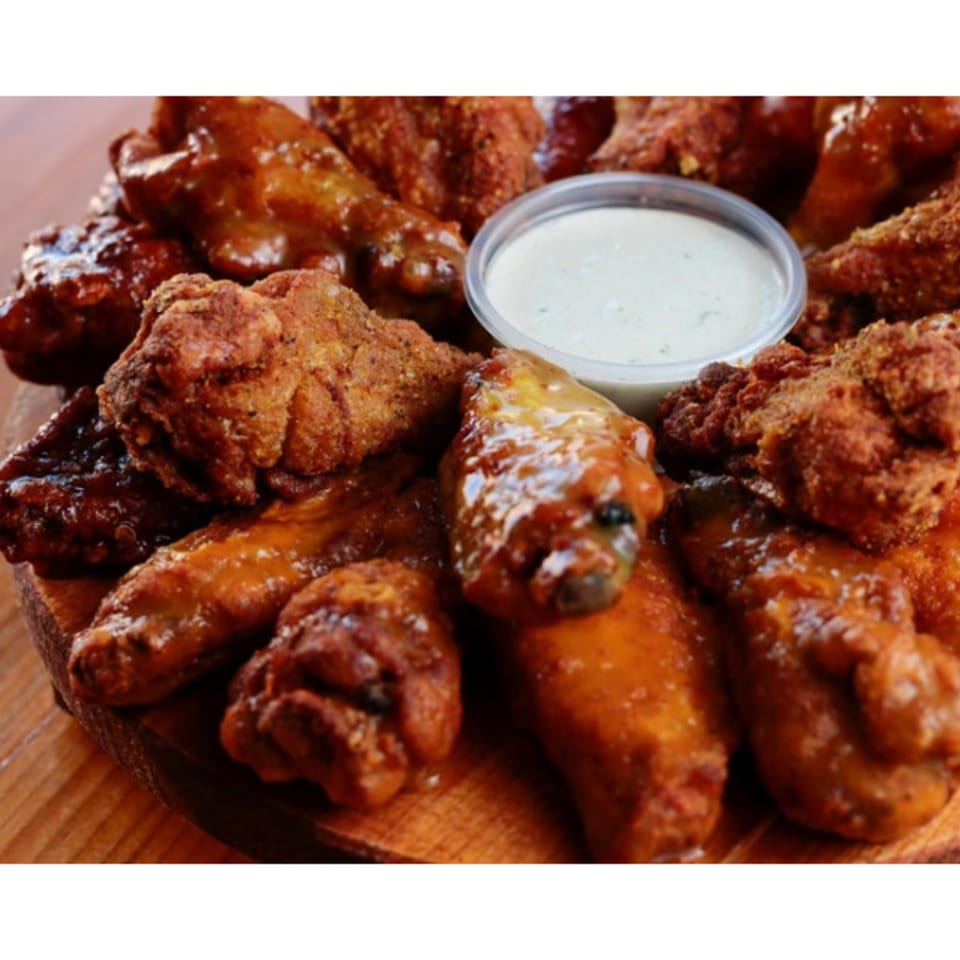 A platter of Brady Brewing Co. chicken wings, some sauced and some dry-rubbed, with a side of ranch.