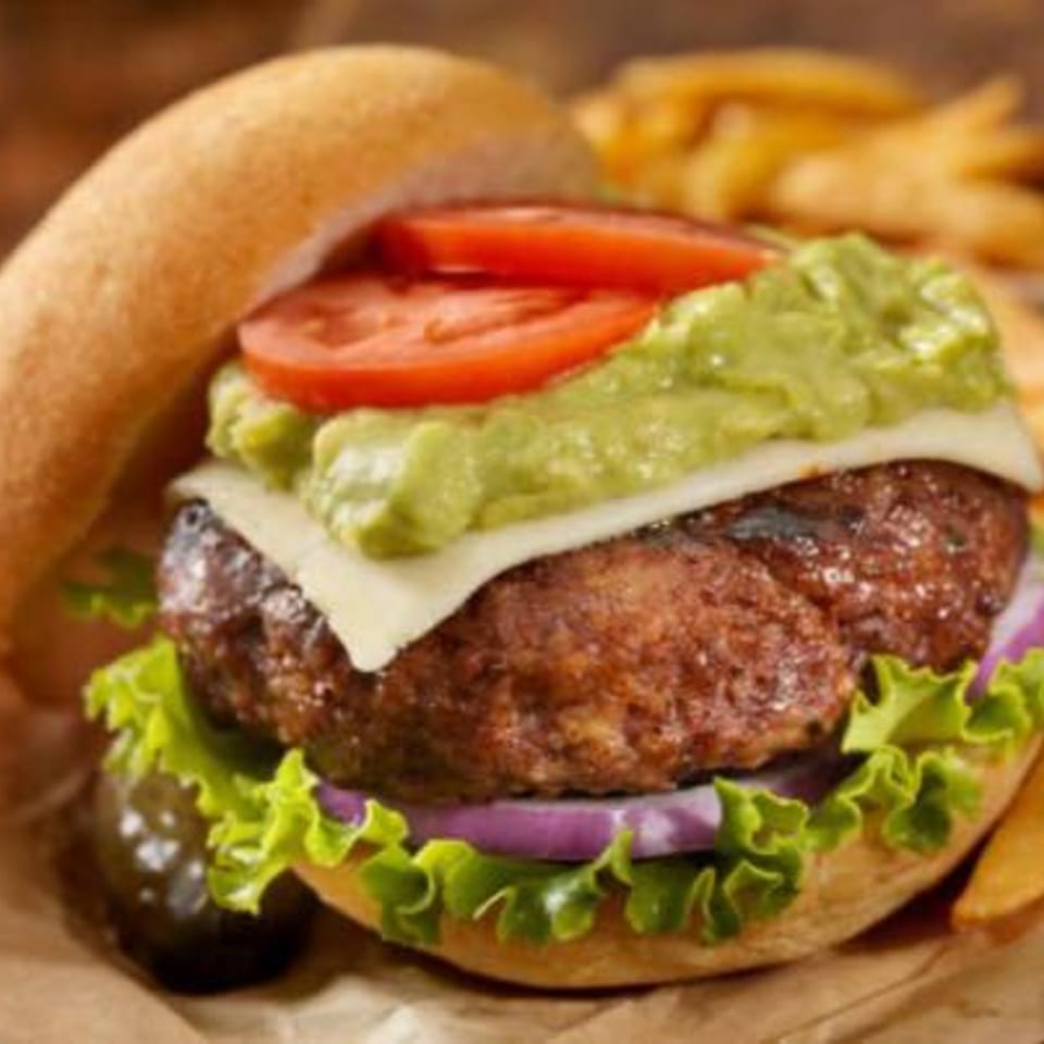 Brady Brewing Co.'s burger with guacamole, cheese, tomato, lettuce, and red onion, with fries.